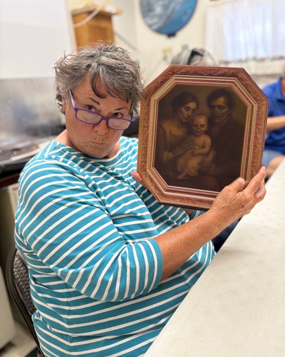 A helper holding up a spooky portrait made for the Halloween party